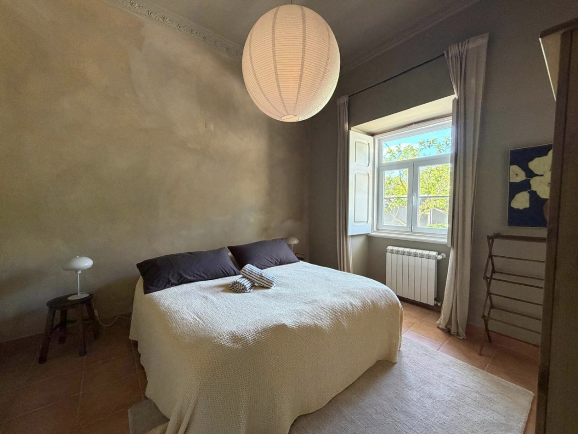 Bedroom with a paper lantern, limewashed walls and shuttered window