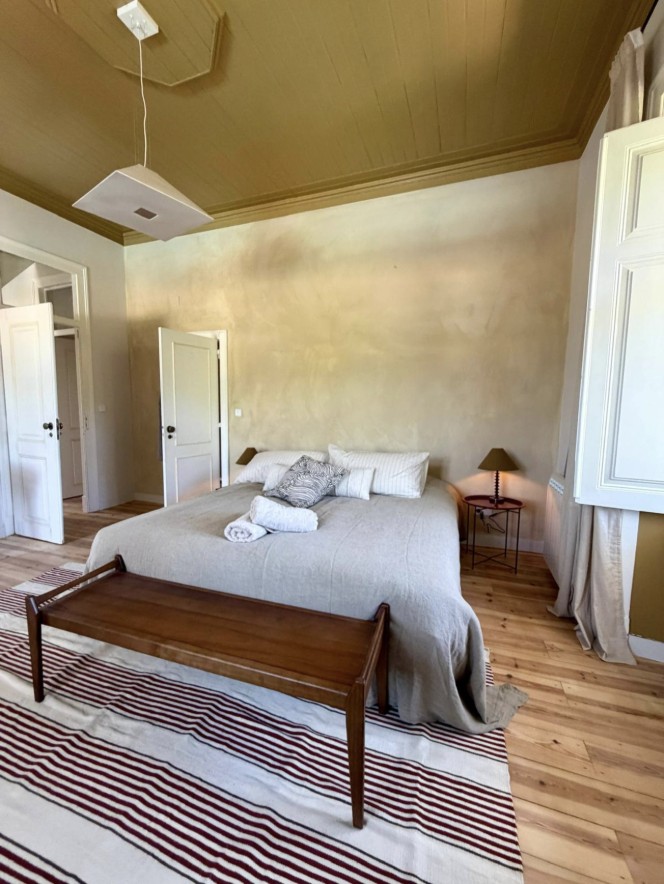 Bedroom with a striped rug, wooden bench and green ceiling