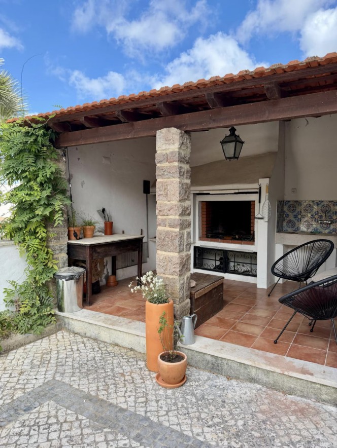 Covered outdoor kitchen with a tiled grill and terracotta floor