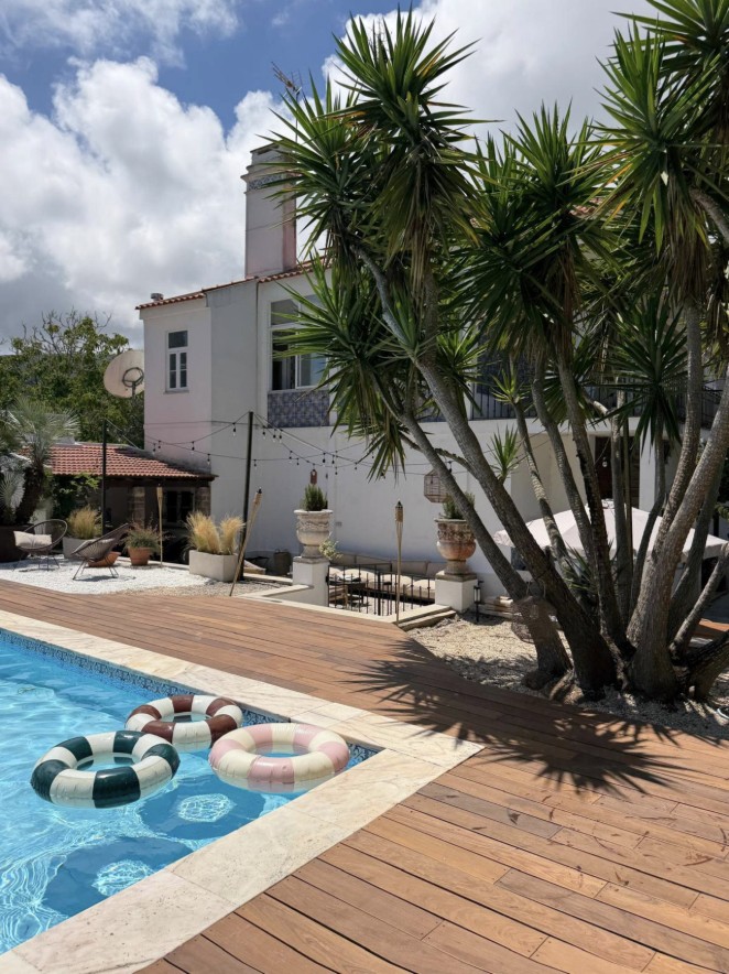 The villa pool and wooden deck framed by palm trees