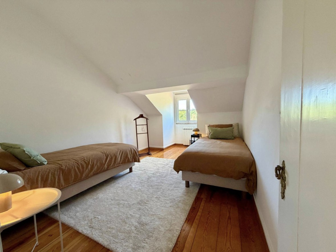 Upstairs bedroom with two twin beds, sloped ceiling and pine floors